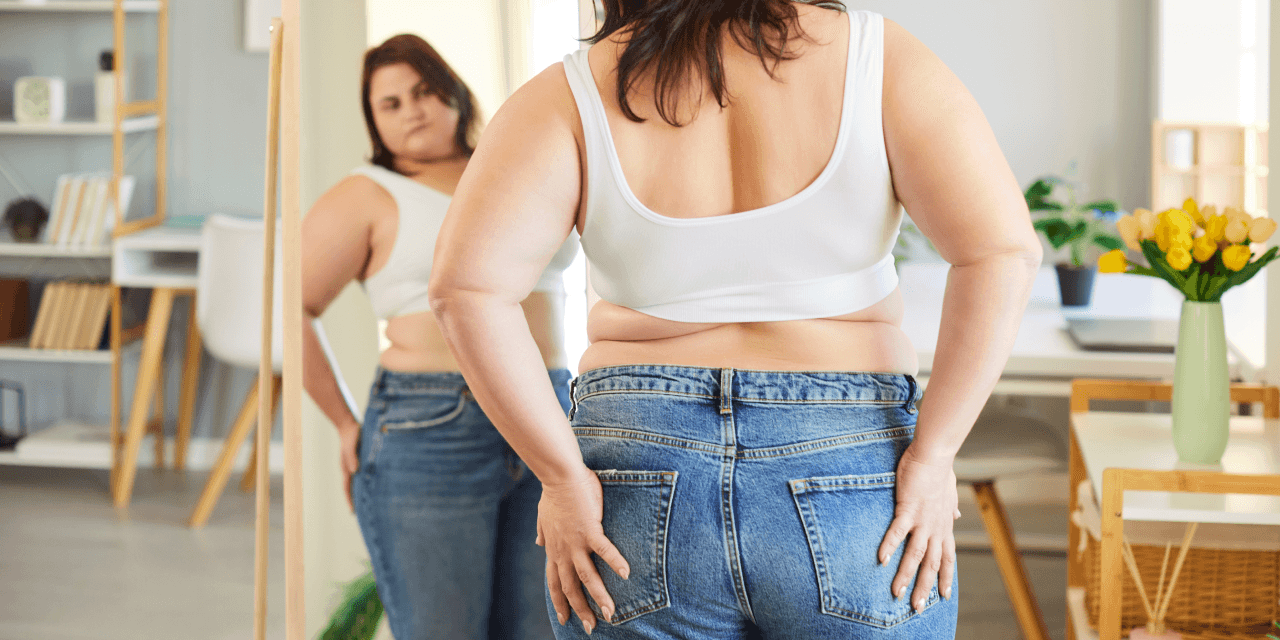 Woman looking at herself in the mirror. She seems conflicted.