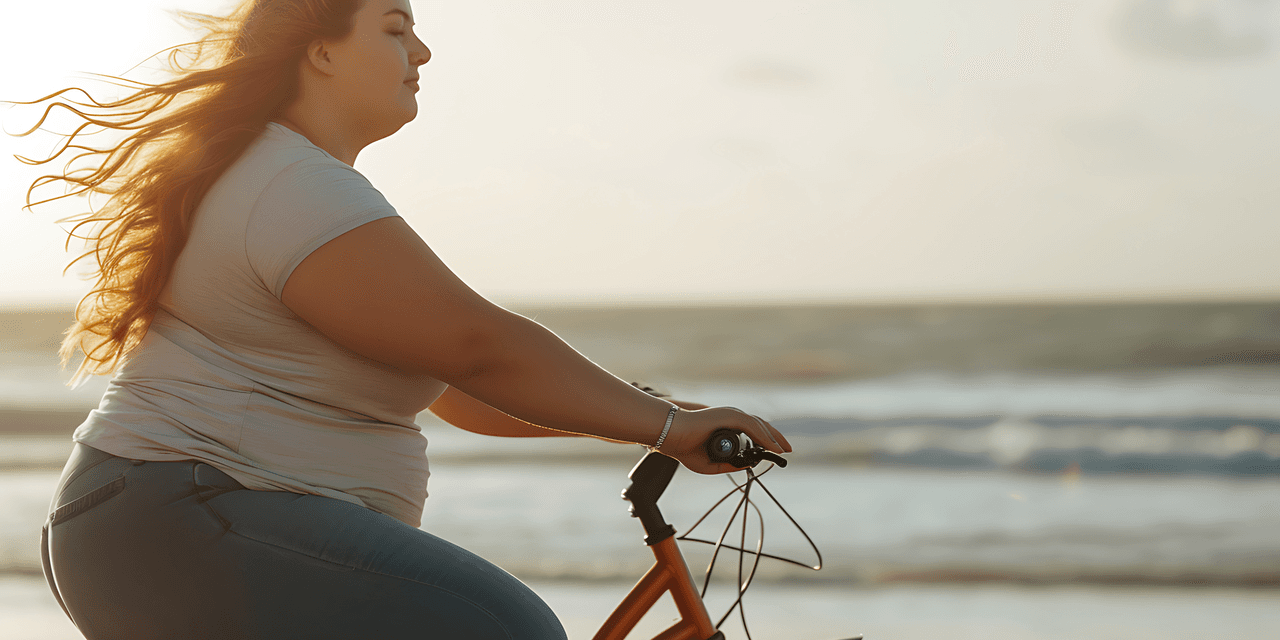 A young woman cycling along the beach at sunrise, looking peaceful.