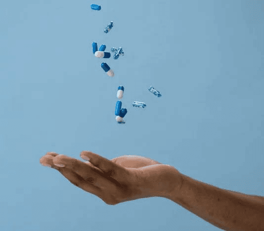 Non-descript capsules that could represent Orlistat for Weight Loss falling into an open palm.