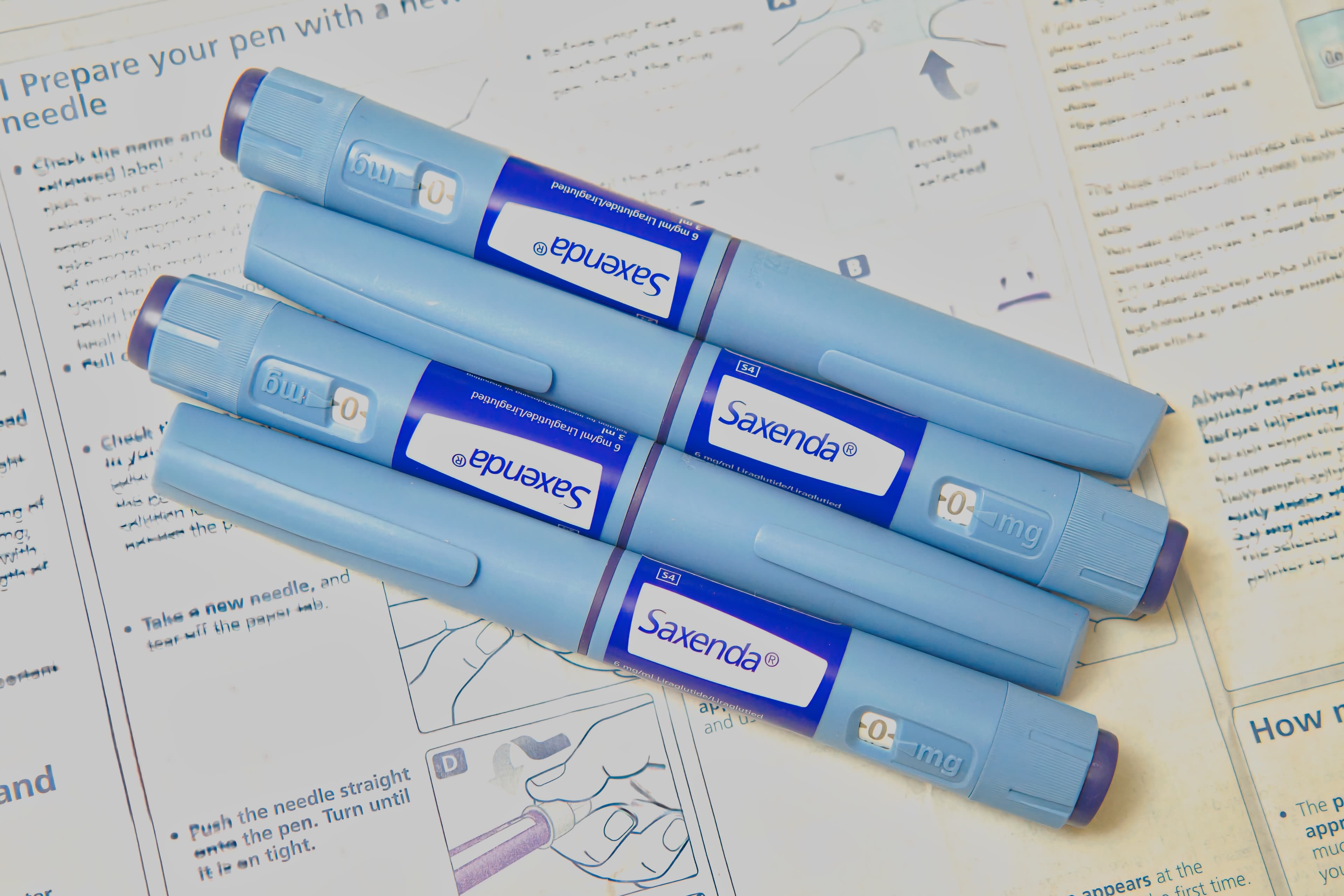 An image of four Saxenda pens on top of a patient information leaflet.