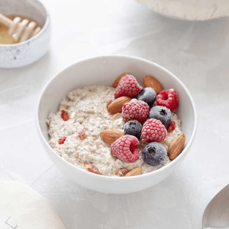 A bowl of porridge with fruits and nuts in it, an example of high-fibre breakfast in a diet.