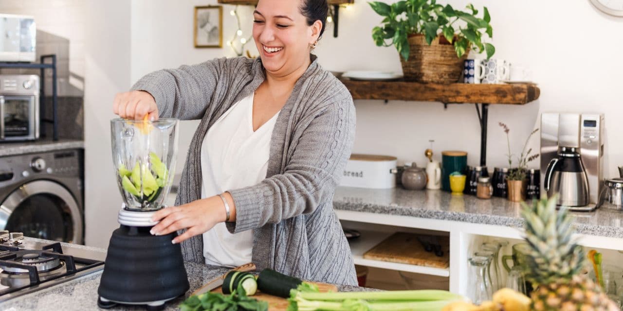 Woman making a green smoothie in a modern kitchen.
