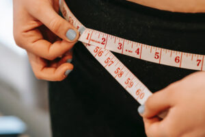 female using tape measure on hips