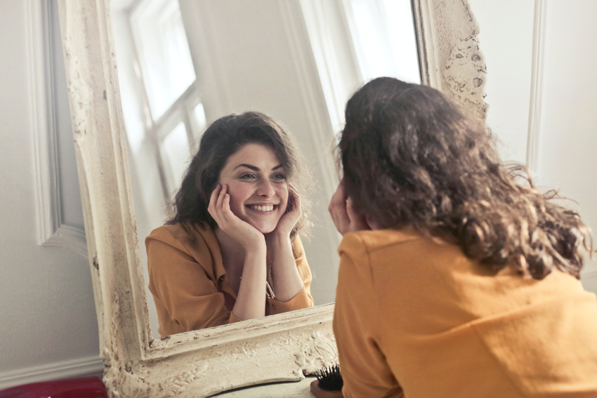 happy female looking at herself in the mirror