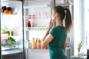 Woman opening fridge to store weight loss pens